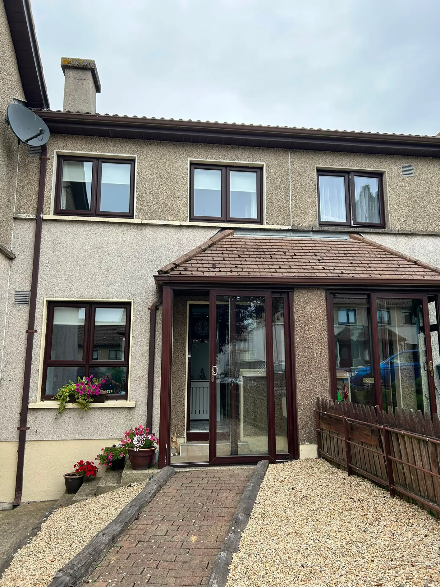 House with dark brown uPVC windows, porch and front door before respraying